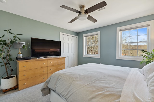 bedroom with a closet, carpet floors, visible vents, and ceiling fan