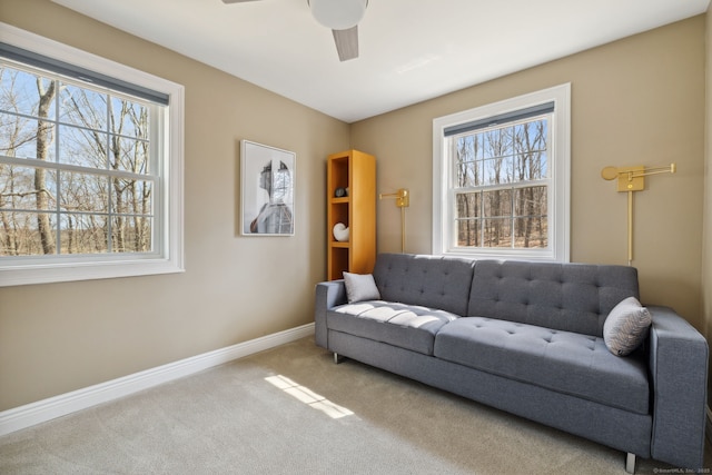 carpeted living area featuring a ceiling fan, baseboards, and a wealth of natural light