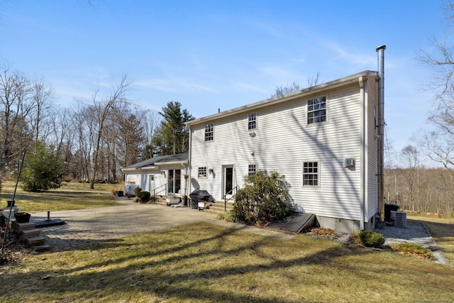 rear view of property featuring entry steps, a yard, and central AC