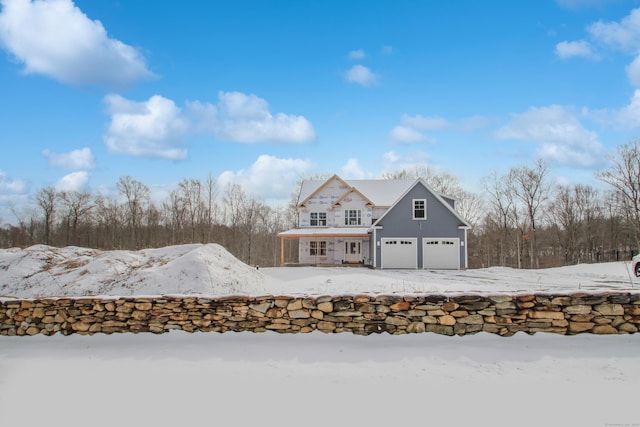 snow covered rear of property featuring an attached garage