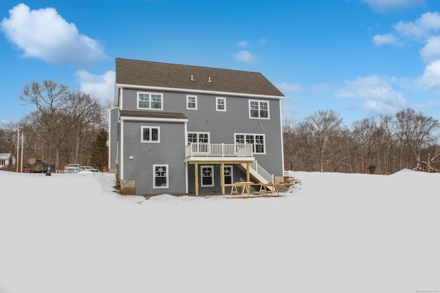 snow covered rear of property featuring a deck and stairway