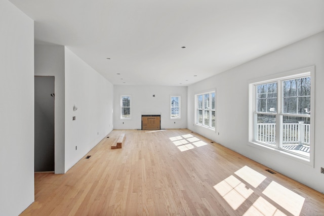 unfurnished living room with visible vents, light wood-style flooring, and a fireplace with flush hearth