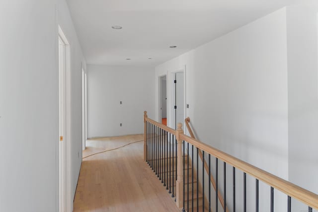 corridor with recessed lighting, an upstairs landing, and wood finished floors