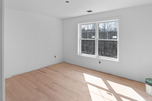 spare room with wood finished floors and visible vents