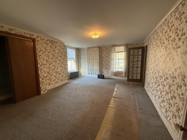 carpeted empty room with a healthy amount of sunlight, ornamental molding, radiator heating unit, and wallpapered walls