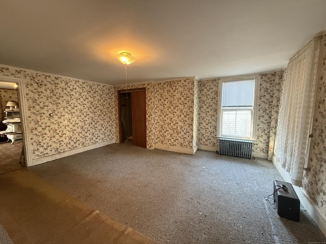 carpeted empty room featuring wallpapered walls and radiator heating unit