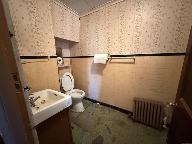 half bathroom featuring vanity, toilet, radiator heating unit, and wallpapered walls