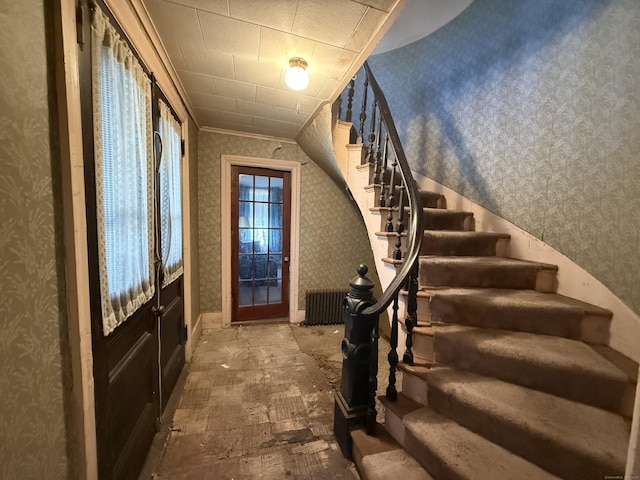 foyer entrance with stairway, ornamental molding, and wallpapered walls