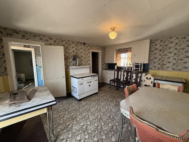 kitchen with white cabinets, wallpapered walls, and dark floors