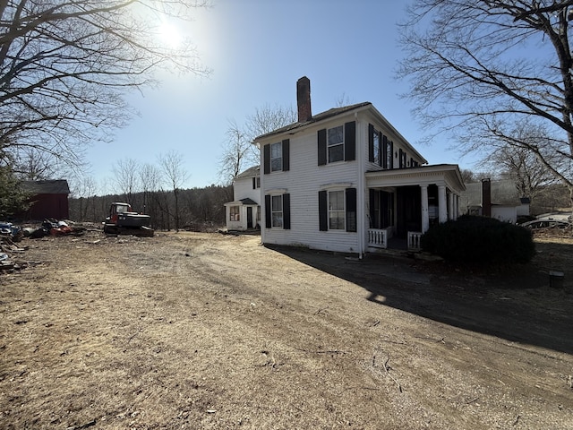 back of house with a porch and a chimney