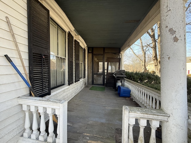 wooden deck featuring a porch and a grill