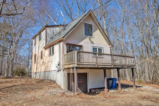 back of house featuring a carport, an attached garage, driveway, and a deck