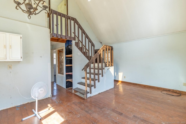 unfurnished living room with baseboards, high vaulted ceiling, stairs, and hardwood / wood-style flooring