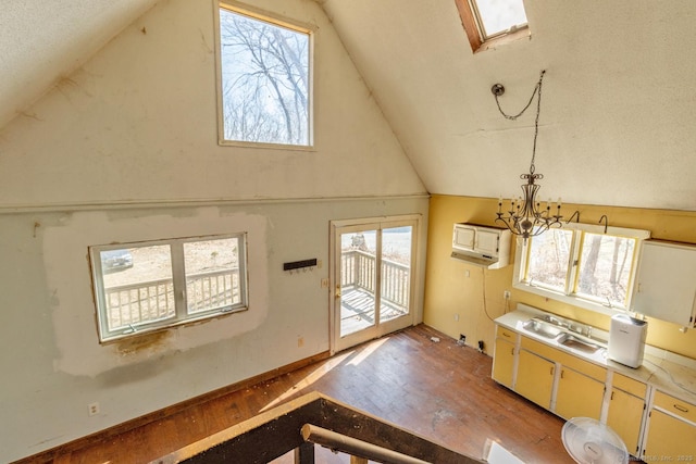 entryway featuring baseboards, light wood finished floors, vaulted ceiling with skylight, a sink, and a chandelier