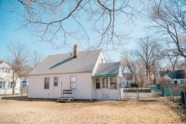 rear view of property featuring roof with shingles, a fenced backyard, a chimney, and a gate