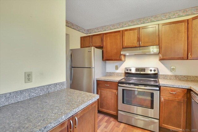 827 Oronoke Rd Apt 2-11, Waterbury, CT 06708 - kitchen with a textured ceiling, light wood-style flooring, light countertops, appliances with stainless steel finishes, and under cabinet range hood