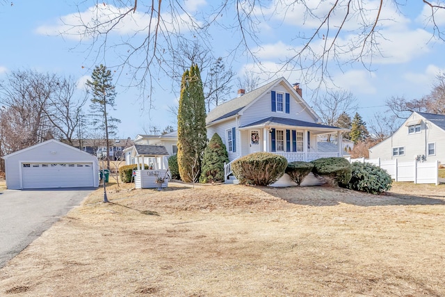 view of front of property featuring an outbuilding, covered porch, a chimney, and a garage