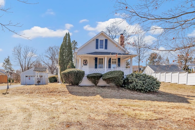 view of front of home with an outbuilding, covered porch, a chimney, and fence