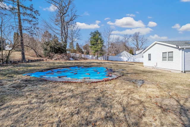 view of swimming pool featuring a yard and fence