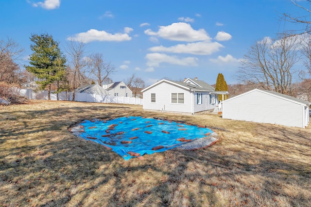 back of property featuring an outdoor structure, a yard, and fence