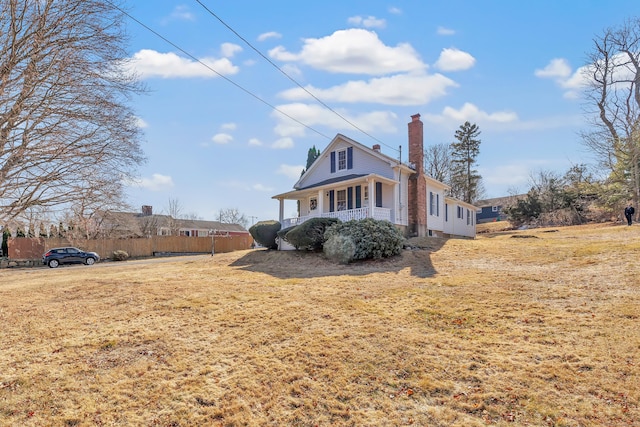 view of front of home featuring a chimney, a porch, a front yard, and fence