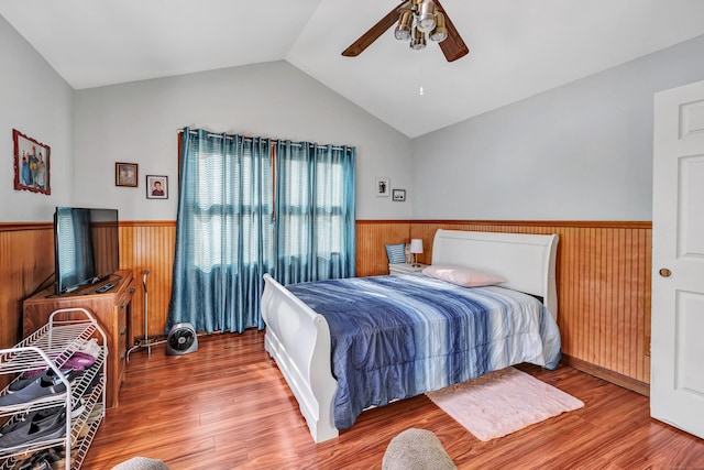 bedroom featuring a wainscoted wall, wood finished floors, and vaulted ceiling