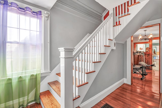 stairway with visible vents, baseboards, an inviting chandelier, and wood finished floors