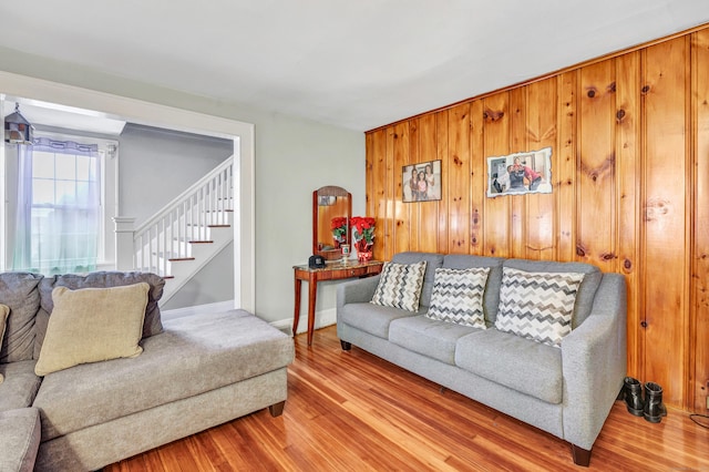 living area with stairway, wood finished floors, baseboards, and wood walls