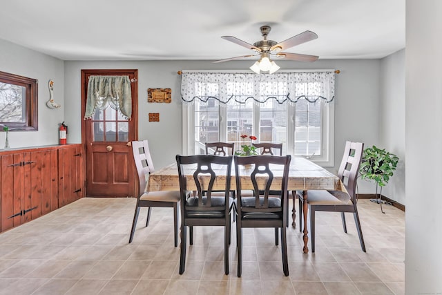 dining area featuring light tile patterned floors, plenty of natural light, wainscoting, and a ceiling fan