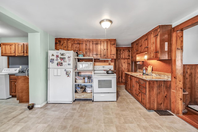 kitchen featuring brown cabinets, a sink, white appliances, light countertops, and washer / dryer