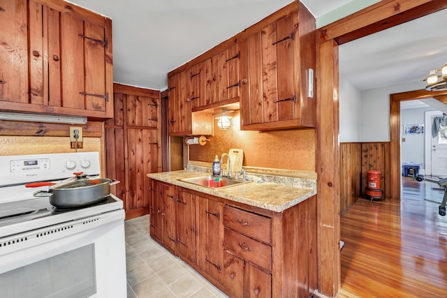 kitchen with electric stove, brown cabinets, and a sink