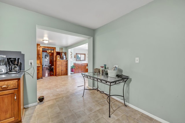 interior space featuring an inviting chandelier, baseboards, and brown cabinets