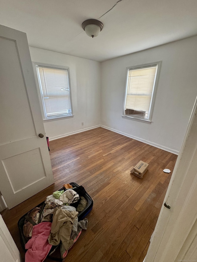 bedroom featuring multiple windows, baseboards, and wood finished floors