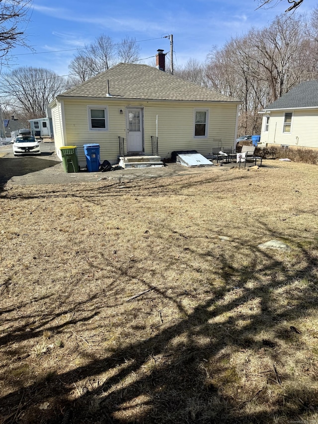 back of property featuring a shingled roof and a chimney