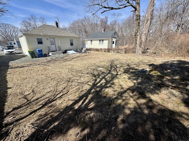 back of property featuring entry steps and a shingled roof