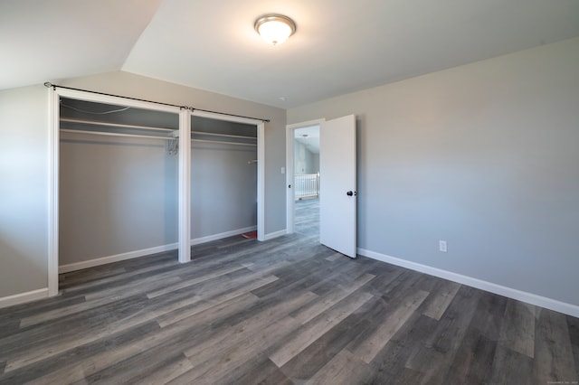 unfurnished bedroom with baseboards, dark wood-style floors, and vaulted ceiling