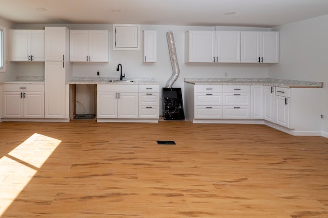 kitchen featuring white cabinets, visible vents, and a sink