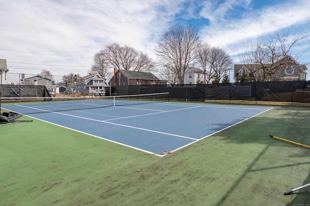 view of tennis court with fence and a residential view