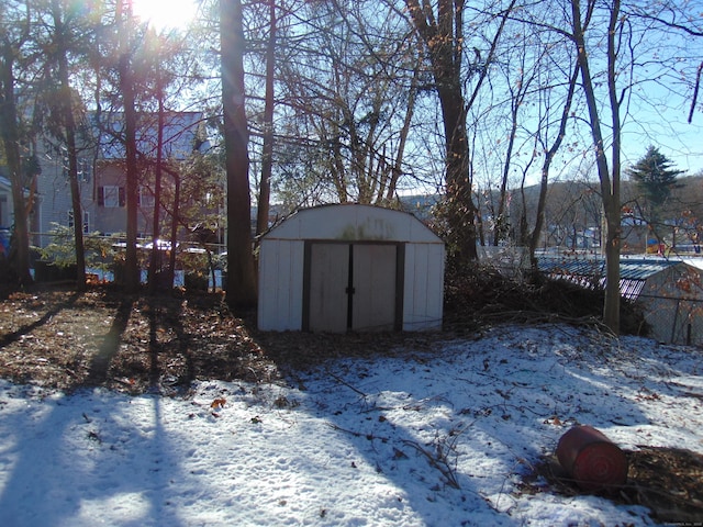 snow covered structure with an outbuilding and a shed