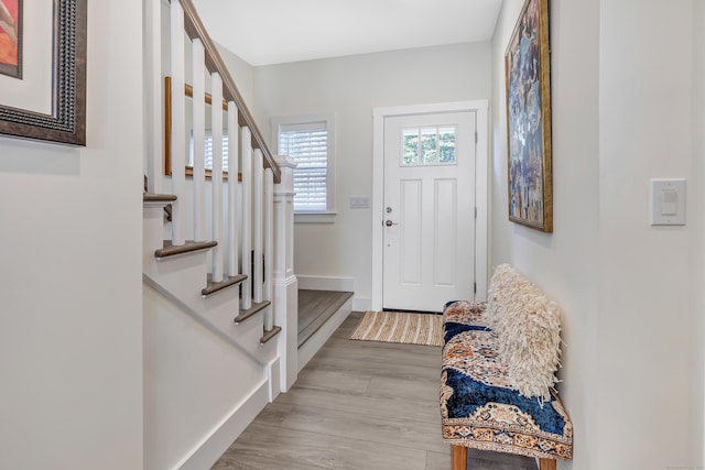 foyer entrance featuring stairway, light wood-style flooring, and baseboards