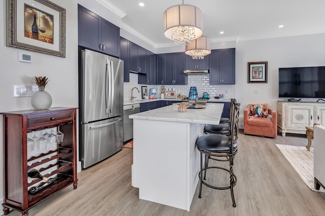 kitchen featuring a center island, a kitchen bar, ornamental molding, light stone counters, and appliances with stainless steel finishes