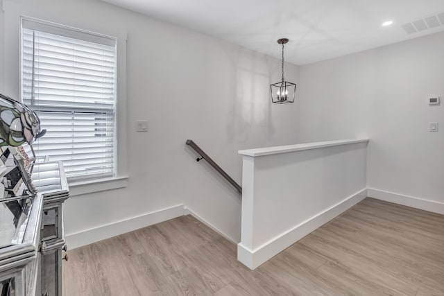 stairway featuring wood finished floors, baseboards, visible vents, and a chandelier