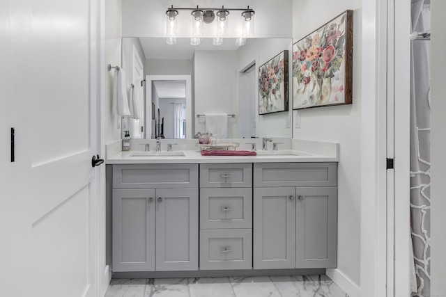 full bath featuring a sink, baseboards, marble finish floor, and double vanity