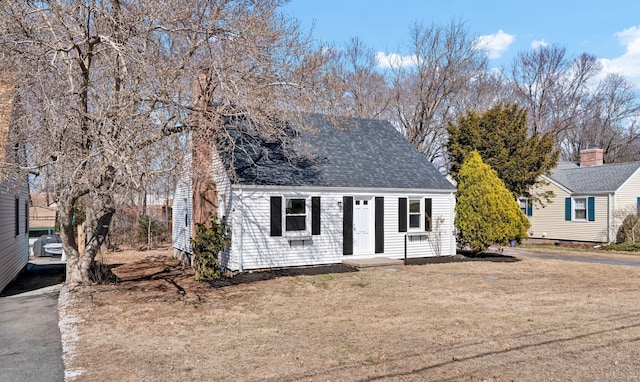 cape cod home with roof with shingles and a front yard