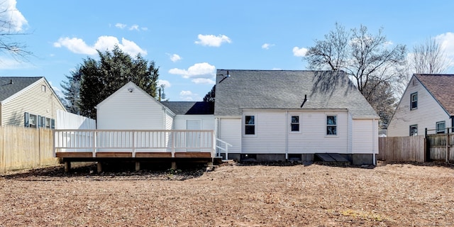 rear view of house with a deck, fence private yard, and a shingled roof