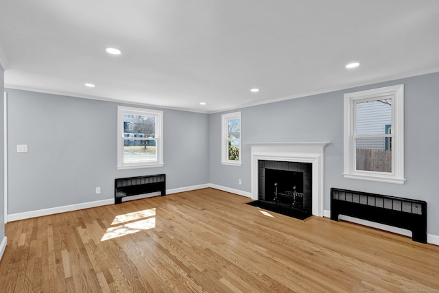 unfurnished living room with crown molding, a brick fireplace, radiator heating unit, and baseboards