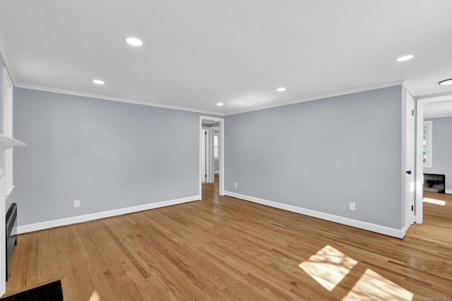 unfurnished living room with baseboards, crown molding, a fireplace, and light wood finished floors