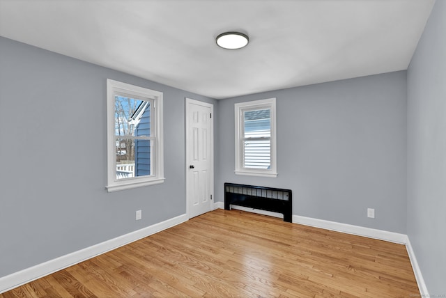 empty room with a healthy amount of sunlight, baseboards, and wood finished floors