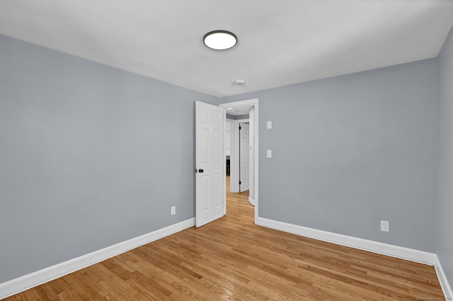 unfurnished room with light wood-type flooring and baseboards