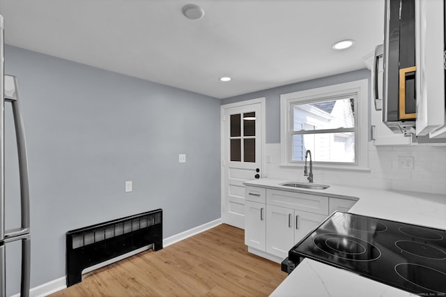 kitchen with a sink, tasteful backsplash, black range with electric cooktop, and light countertops